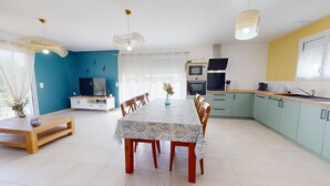 A modern kitchen with a dining area, a TV, and a large window. - Serenity – Family home with a garden and Wi-Fi in (Saint-Jean-de-Monts)