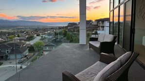 Un balcó amb vistes a una zona residencial i muntanyes durant el capvespre.