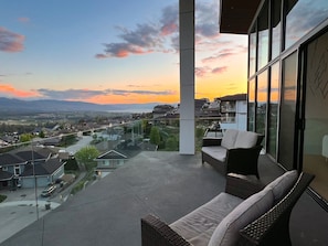 Ein Balkon mit Blick auf ein Wohngebiet und Berge im Abendlicht.