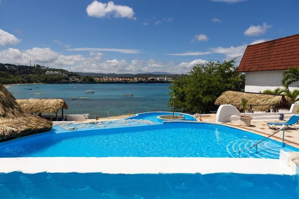 Ein Pool mit Blick auf das Meer und ein Gebäude mit rotem Dach.