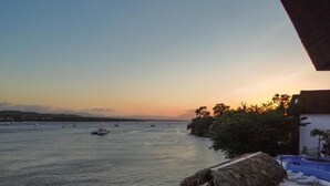 Vista sul mare con una struttura a tetto di paglia, poltrona a sdraio e zona piscina.