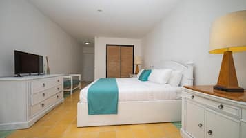 Een slaapkamer met een bed, televisie, lamp en een kledingkast.