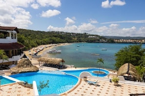 Un complexe hôtelier doté d’une piscine, d’une plage et offrant une vue sur l’océan.