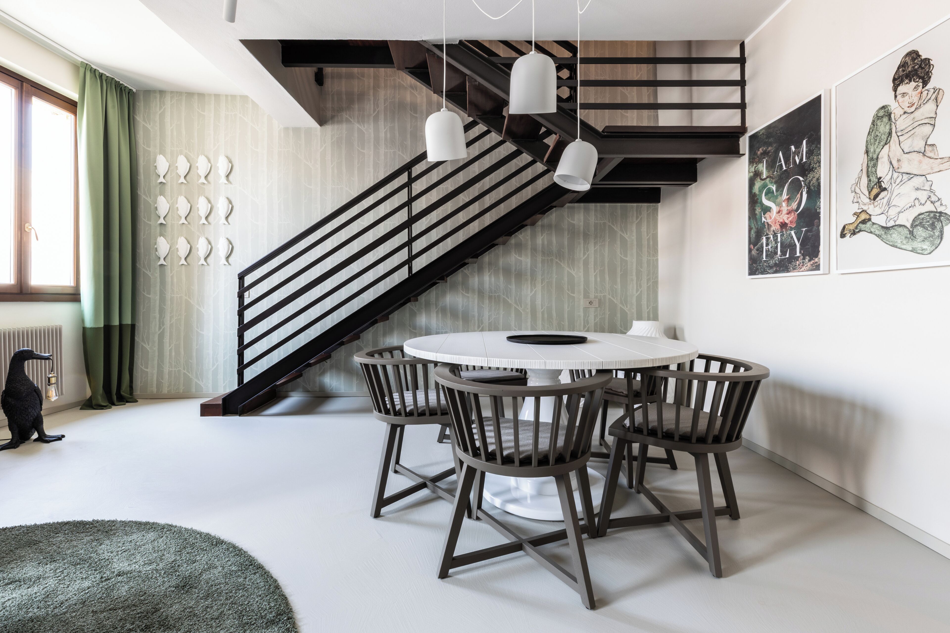 Ein modernes Interieur mit einer Treppe, einem runden Esstisch und Stühlen.