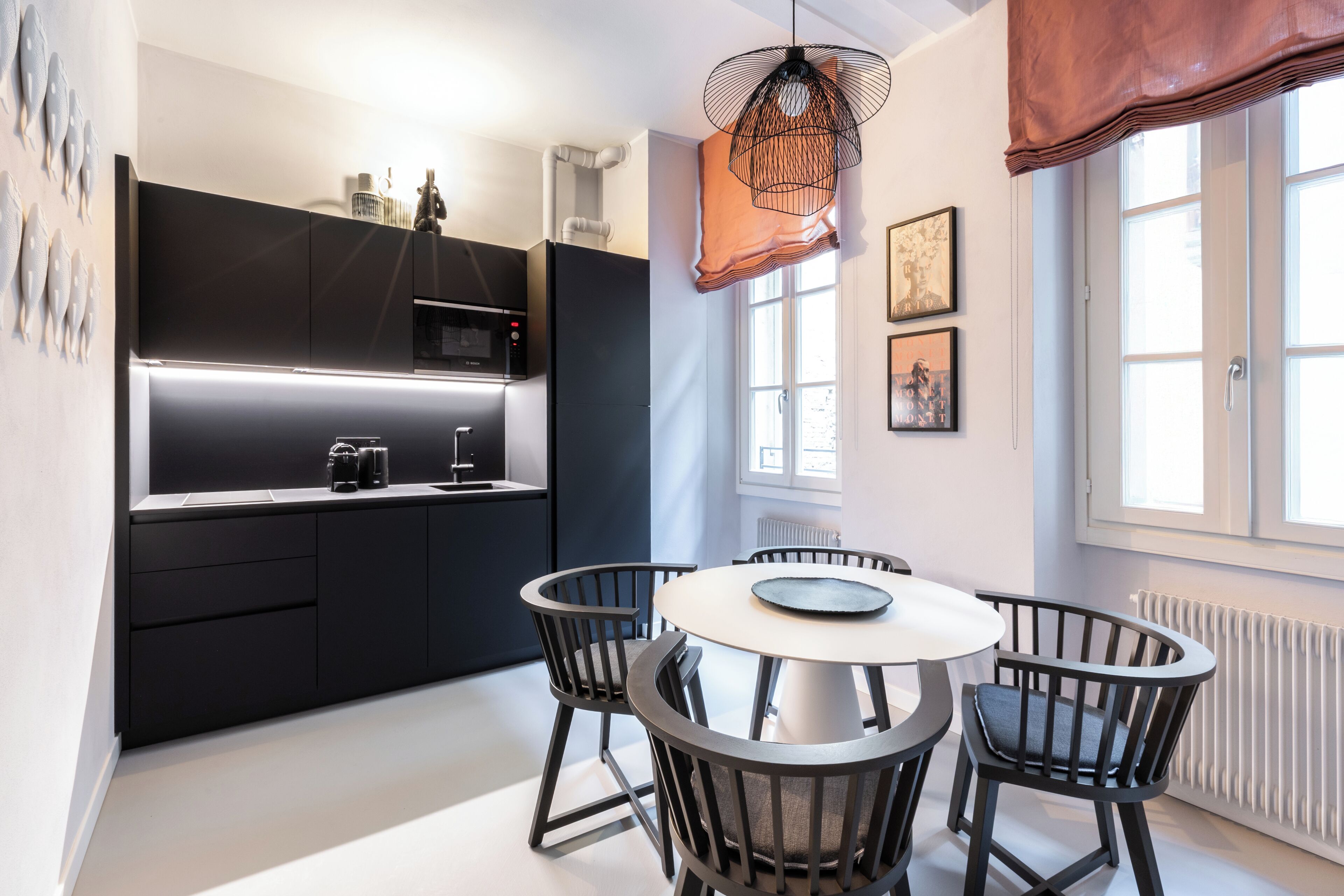 Una cocina moderna con armarios oscuros, una mesa de comedor redonda y sillas negras.