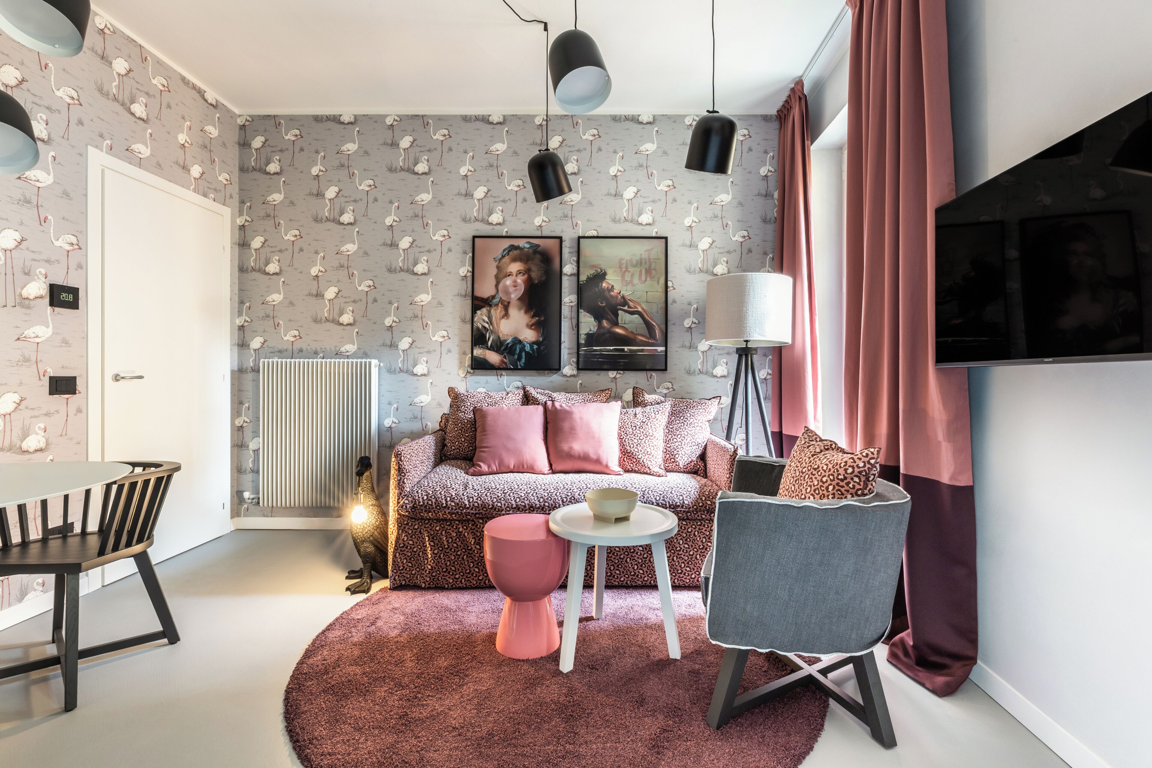 A modern bedroom with a patterned wallpaper, a sofa, a dining table, and a chair.