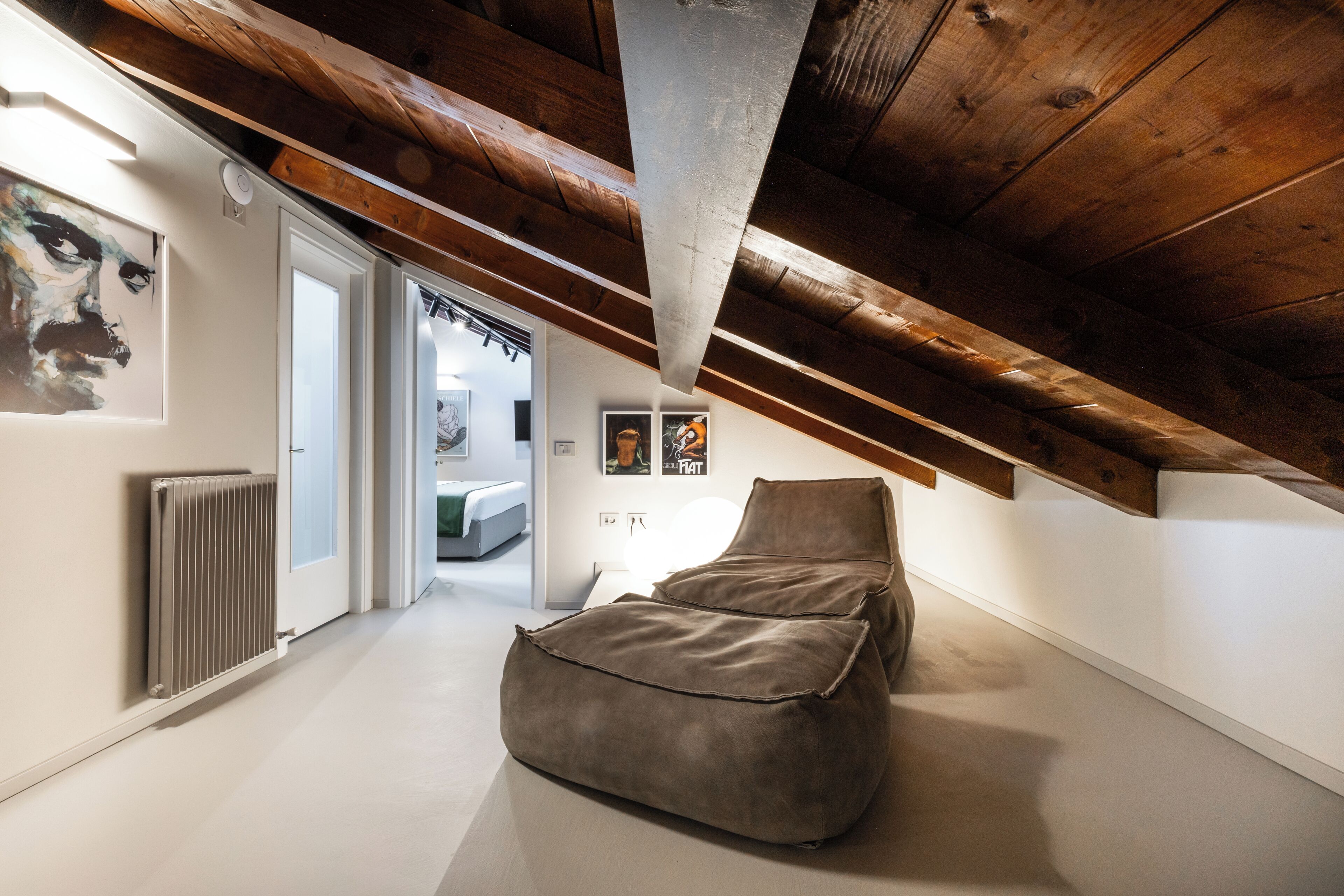 A modern loft bedroom with a sloped ceiling, a large window, and a minimalist design.