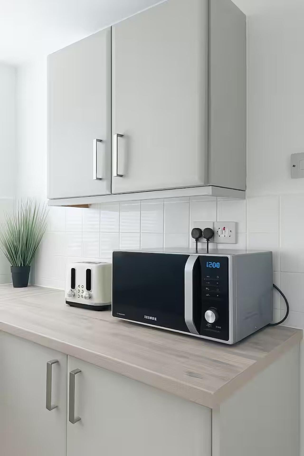A kitchen with a microwave, toaster, and cabinets.