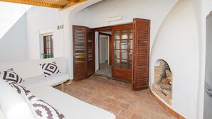 A white room with a wooden door, a white sofa with patterned cushions, and a tiled floor. - Gaviotas apartment C75 (Manilva)