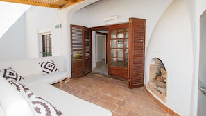 A white room with a wooden door, a white sofa with patterned cushions, and a tiled floor. - Gaviotas apartment C75 (Manilva)
