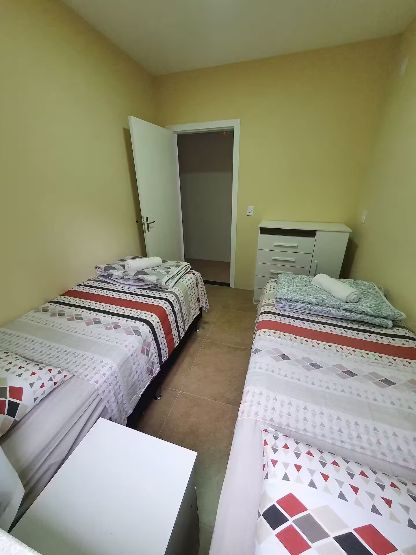 Une chambre avec deux lits, une armoire et une petite table.