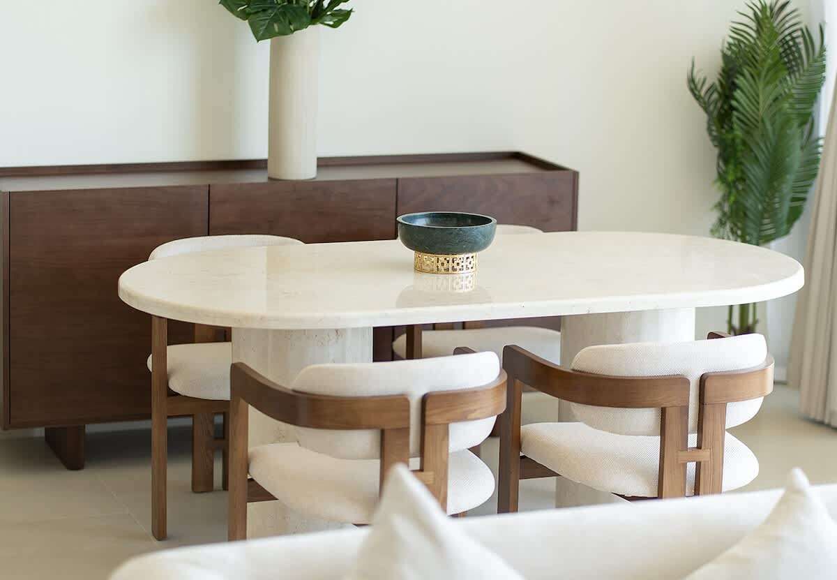 Un tavolo rotondo da pranzo con sei sedie, una ciotola decorativa e un mobiletto in legno sullo sfondo.