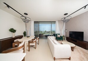Una sala de estar moderna con sofá, mesa de comedor, sillas, televisor y balcón con vistas.
