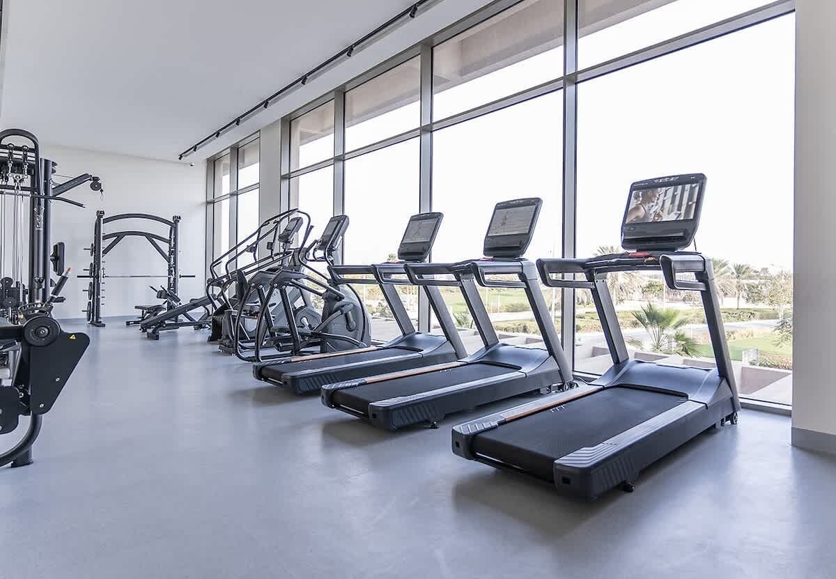 Una palestra con tapis roulant, macchinari per pesi e una grande finestra.