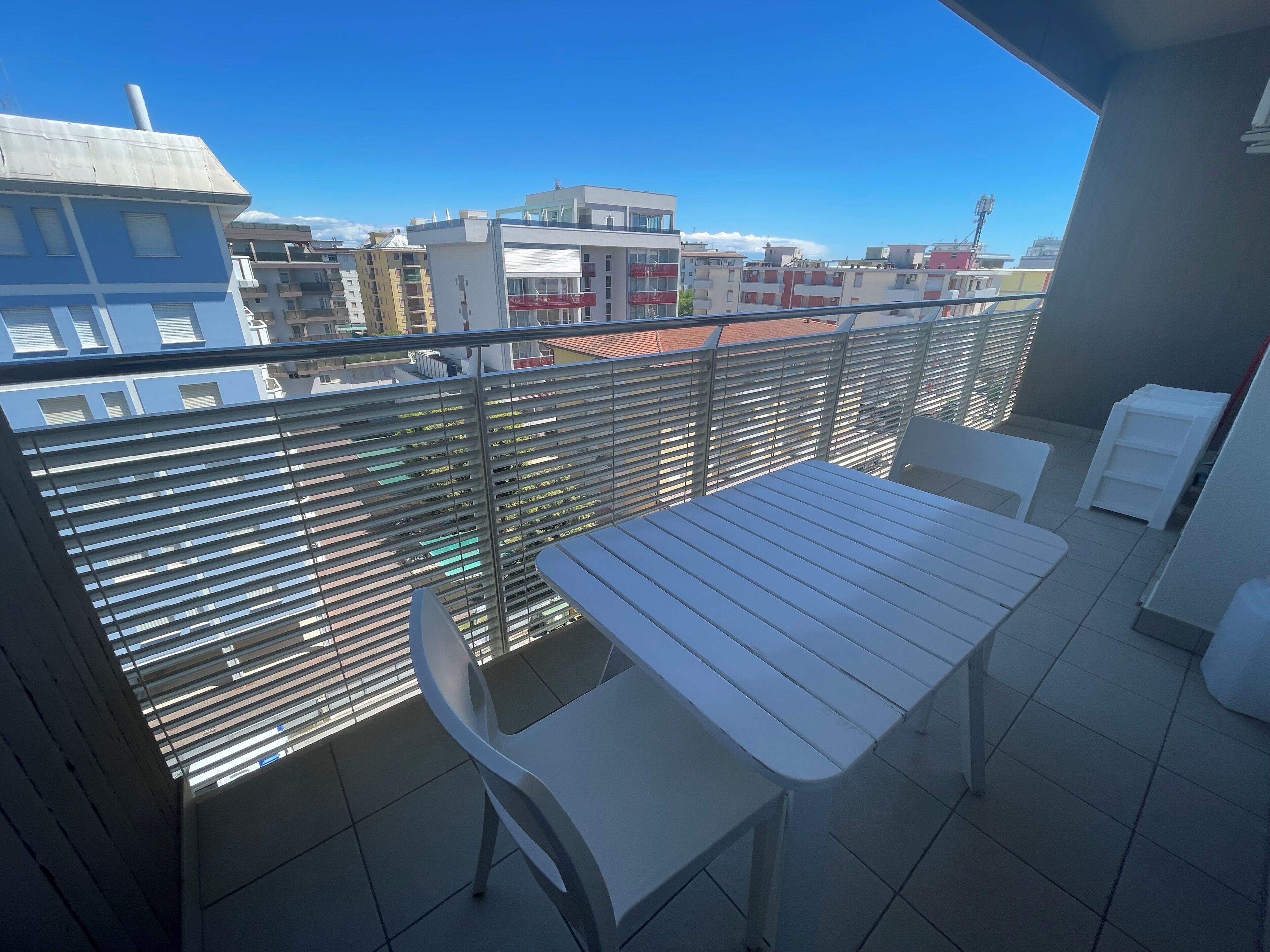 Ein Balkon mit Tisch und Stühlen, einem Metallgeländer und Blick auf Gebäude.