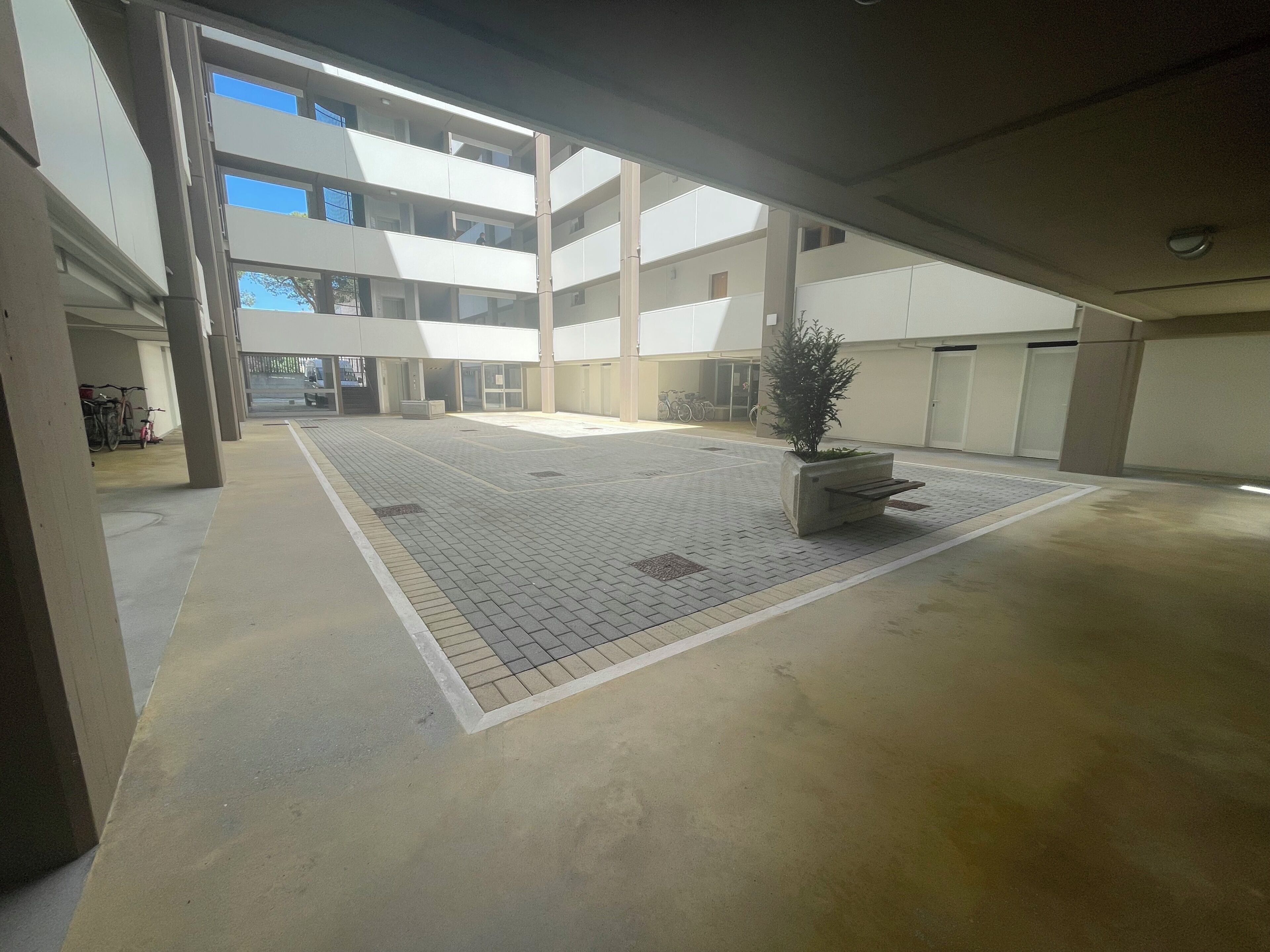 A multi-level parking structure with a central open area, concrete flooring, and a potted plant.