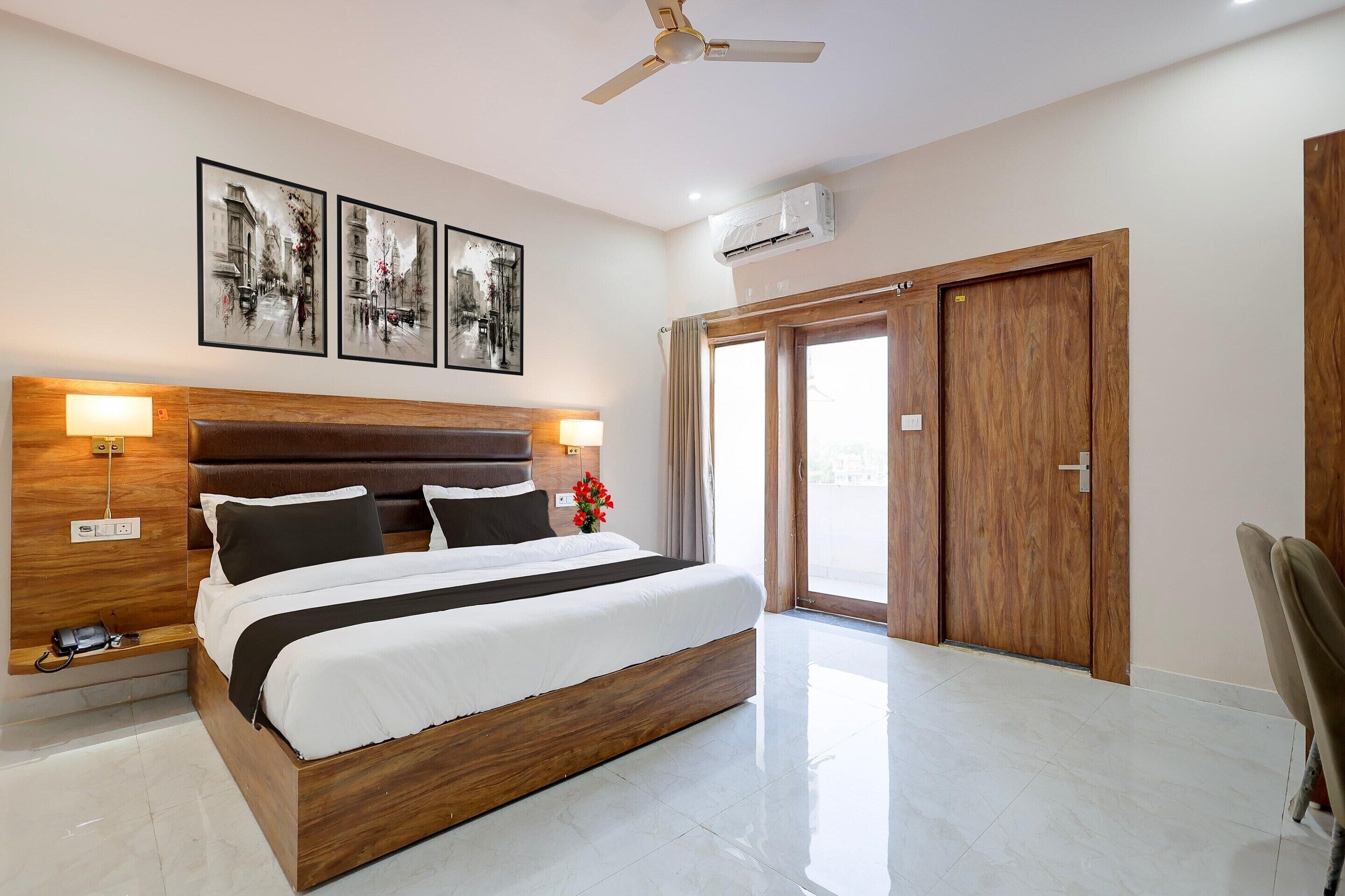 A hotel room with a large bed, two bedside lamps, a ceiling fan, and three framed pictures on the wall.