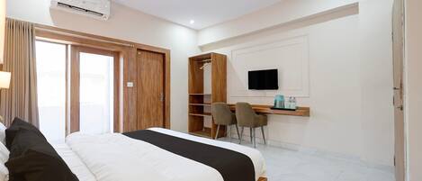 Una habitación de hotel con cama, escritorio, televisor y armario.