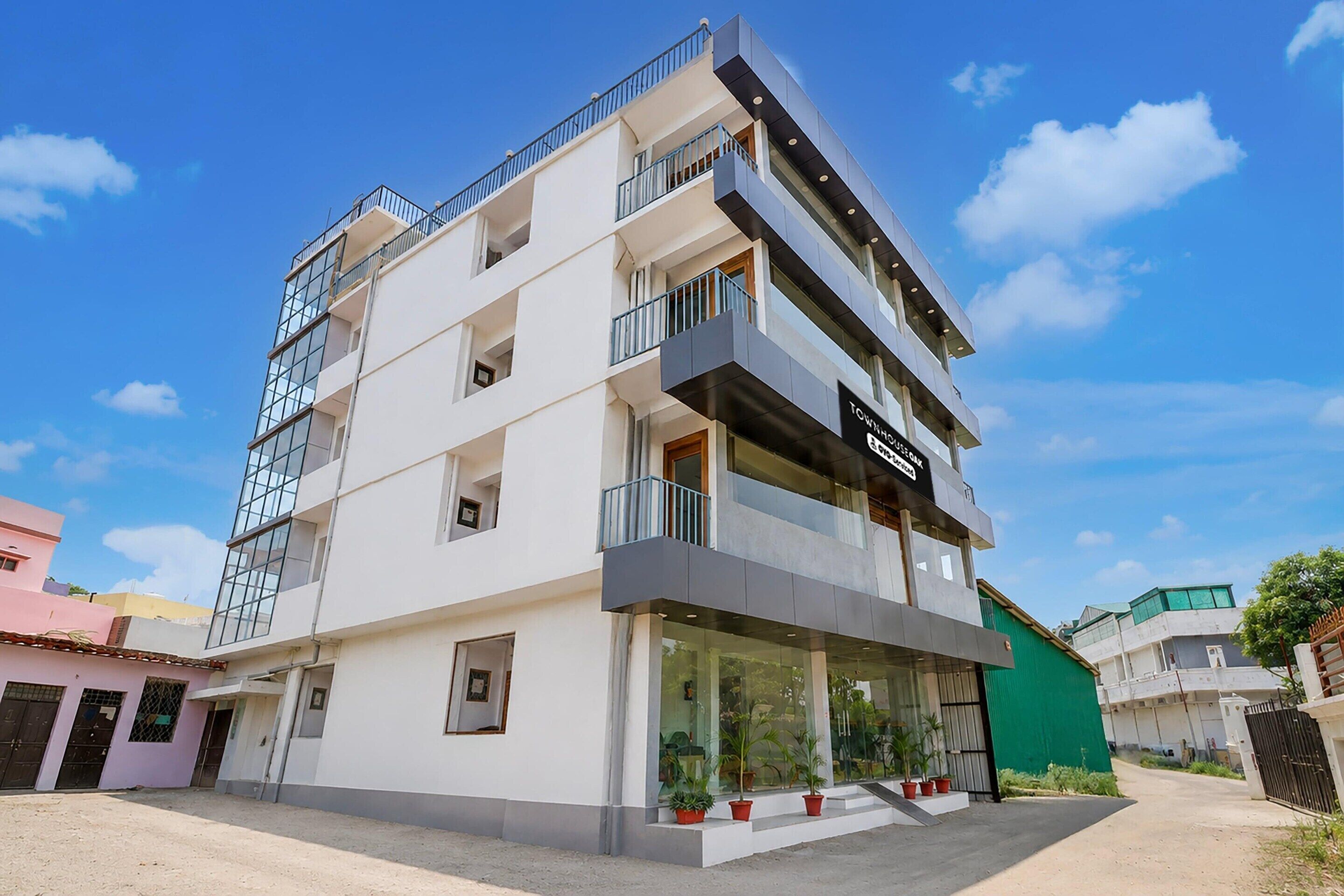 A multi-story residential building with balconies, a visible sign for a business, and a gated entrance.