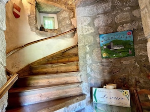 A stone staircase with wooden steps, a small window, and a sign for 'Château de Lescure Chambres d'hôtes B&B.'