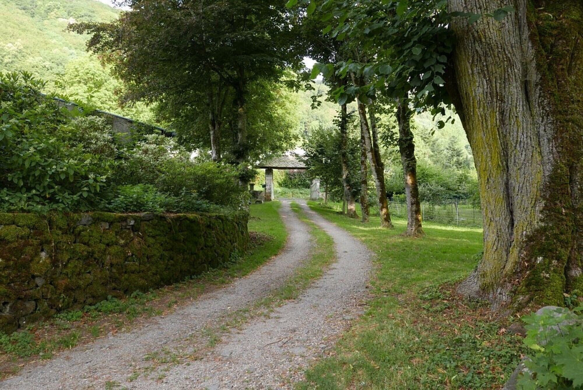 A gravel path leading to a stone structure in a wooded area.