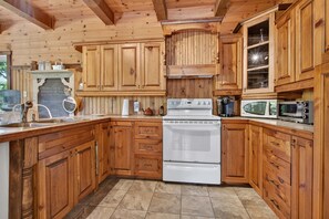 A kitchen with wooden cabinets, a stove, a microwave, and a chalkboard with writing. - Spa & Nature Retreat - Le Bercail (Entrelacs)