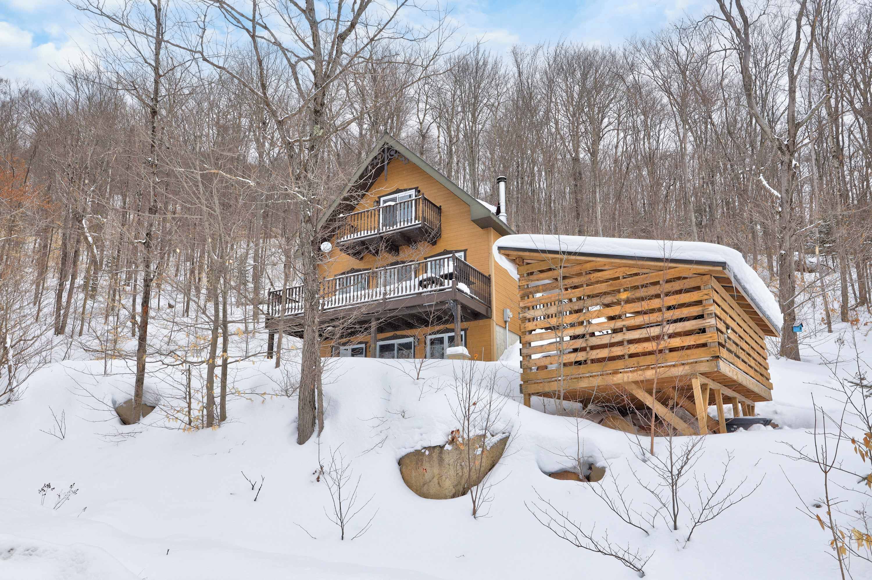 A cabin with a balcony, surrounded by snow-covered trees.