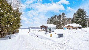 A snow-covered road with a wooden structure and a small building with a snow-covered roof. - Spa & Nature Retreat - Le Bercail (Entrelacs)