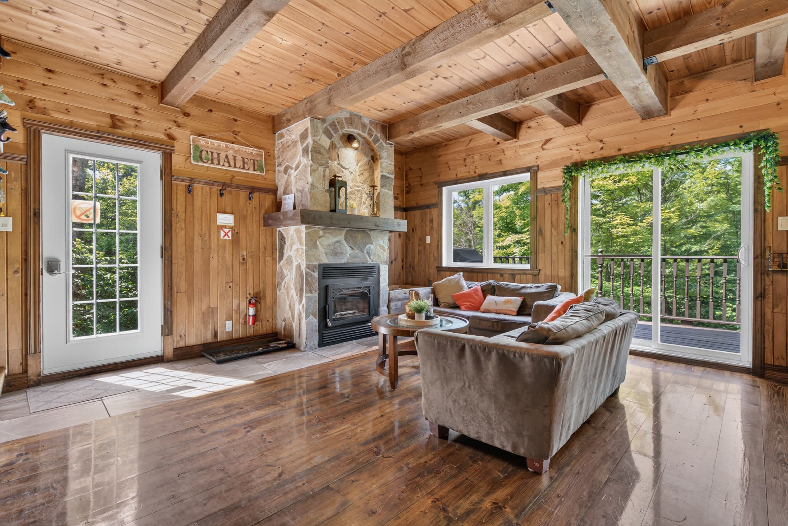 Een houten interieur met een stenen openhaard, een bank en een deur met de tekst 'CHALET'.