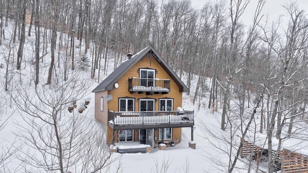 A two-story house with a balcony, surrounded by snow-covered trees. - Spa & Nature Retreat - Le Bercail (Entrelacs)
