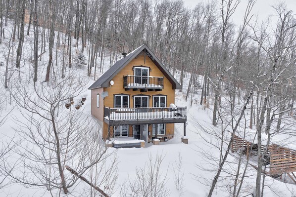 A two-story house with a balcony, surrounded by snow-covered trees. - Spa & Nature Retreat - Le Bercail (Entrelacs)