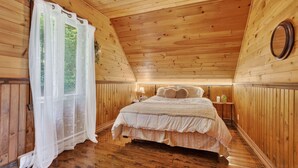 A cozy wooden room with a bed, a nightstand, and a window with sheer curtains. - Spa & Nature Retreat - Le Bercail (Entrelacs)