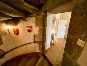 A stone staircase with wooden steps leading to a room with a white door and a coat rack.