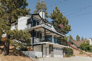Una casa moderna de dos pisos amb garatge, grans finestres i un balcó.