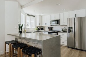 A modern kitchen with white cabinets, stainless steel appliances, and a central island with stools.