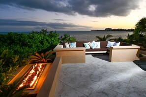 Um terraço com um sofá, lareira e vista para o mar.