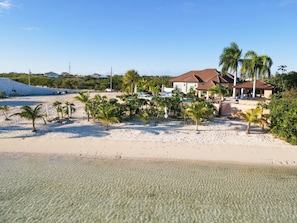 Ein Strandgrundstück mit einem Haus, Palmen und freiem Blick auf den Ozean.