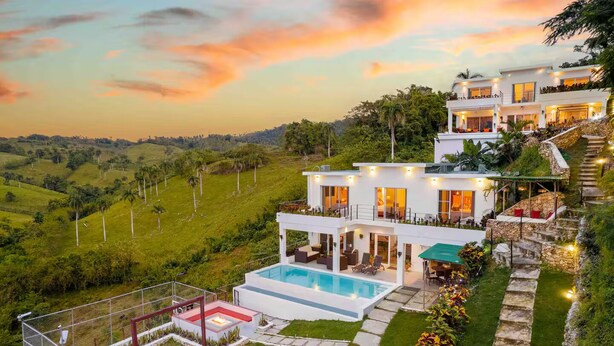 A multi-story house with a swimming pool, outdoor seating, and a stone staircase.