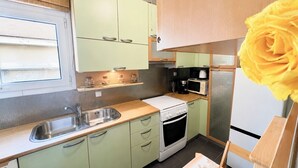 Une cuisine de taille réduite, équipée d’un évier, d’une cuisinière, d’un four à micro-ondes et d’un réfrigérateur.