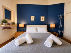 A hotel room with a bed, two bedside lamps, a nightstand, a mirror, a coat rack, and two framed pictures on the wall. - Urban Escape With Acropolis View by MPS (Athina)