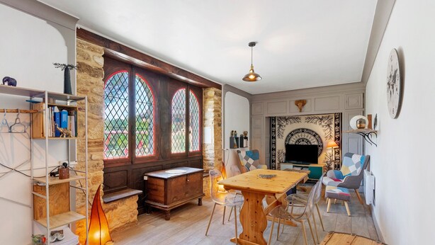 A cozy living room with a wooden table, chairs, a fireplace, and a bookshelf. - La Maison Dô – Stone House with Pool for 4 Guests Near Dordogne (Frayssinet-le-Gélat)