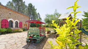 A stone building with arched windows and a wooden playhouse. - La Maison Dô – Stone House with Pool for 4 Guests Near Dordogne (Frayssinet-le-Gélat)