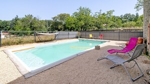 A rectangular swimming pool with a white edge, surrounded by a gravel area. There are two lounge chairs, one with a pink cover and another with a grey cover. A yellow floating pool noodle is visible in the water. - La Maison Dô – Stone House with Pool for 4 Guests Near Dordogne (Frayssinet-le-Gélat)