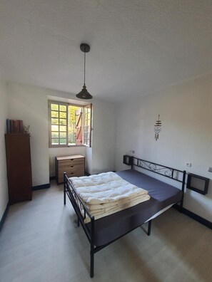 Quarto com cama, escrivaninha, armário, janela e televis ão fixada na parede.