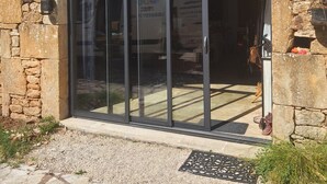 Een gebouw van steen met een grote, rondboogvormige ingang, een metalen deur en een klein buitenruimte met een deurmat.