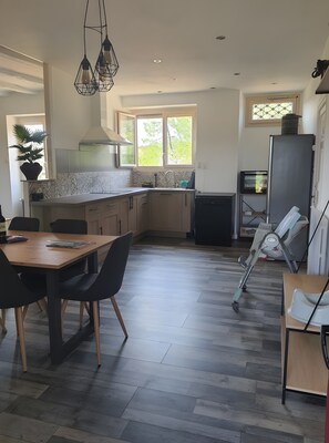 Una cocina moderna con zona de comedor, suelo de madera y vistas al exterior.