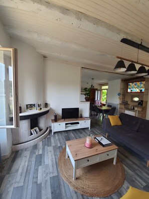 Una sala de estar moderna con televisor, sofá, mesa de centro y chimenea.