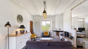 Una sala de estar con un sofá, una lámpara, un reloj y una ventana.