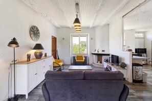 A living room with a sofa, a lamp, a clock, and a window.