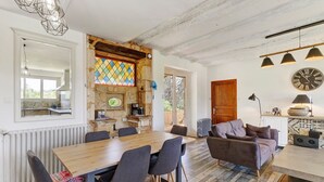 Una cocina amplia con una mesa y sillas de madera, un muro de piedra con un vitral y un techo rústico.